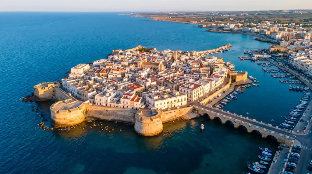 Panoramic aerial view of the ancient limestone island of Gallipoli Puglia and its historic stone bridge at sunset.